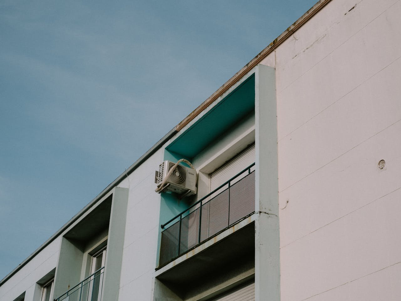 extra-programs-img A low angle view of a modern apartment building featuring a balcony and air conditioner unit.